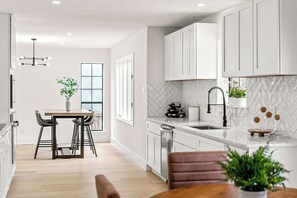 A modern kitchen with white cabinets, a herringbone backsplash, and a central island. - Fully Renovated Furnished Home in Hurst – Perfect for Mid-Term Stays (Hurst)
