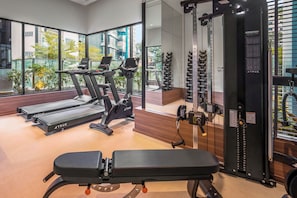 A gym with treadmills, a bench, and weight machines. - Weave Suites - Novena (Singapore)