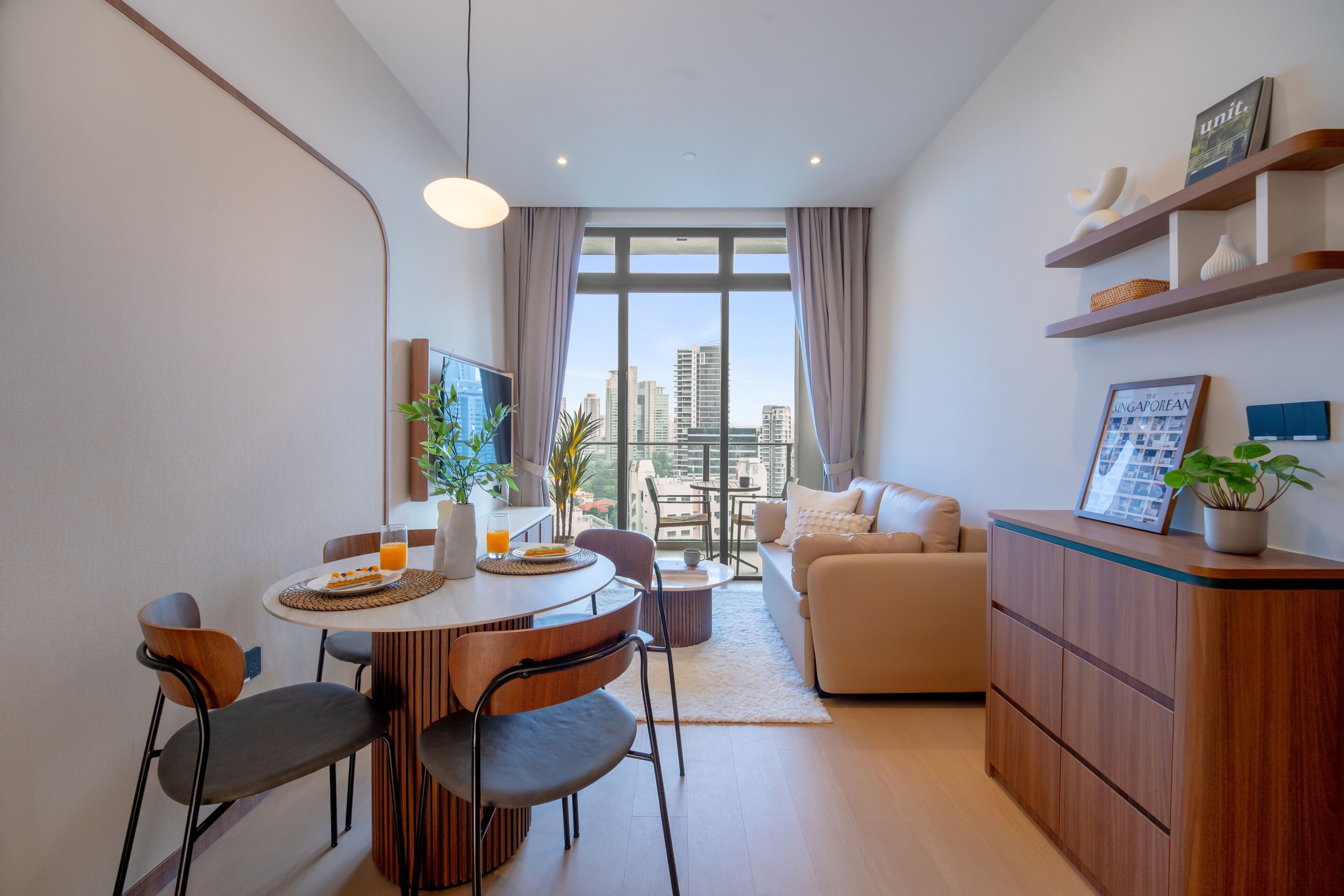 A modern living room with a dining area, a sofa, a coffee table, and a view of the cityscape through large windows.