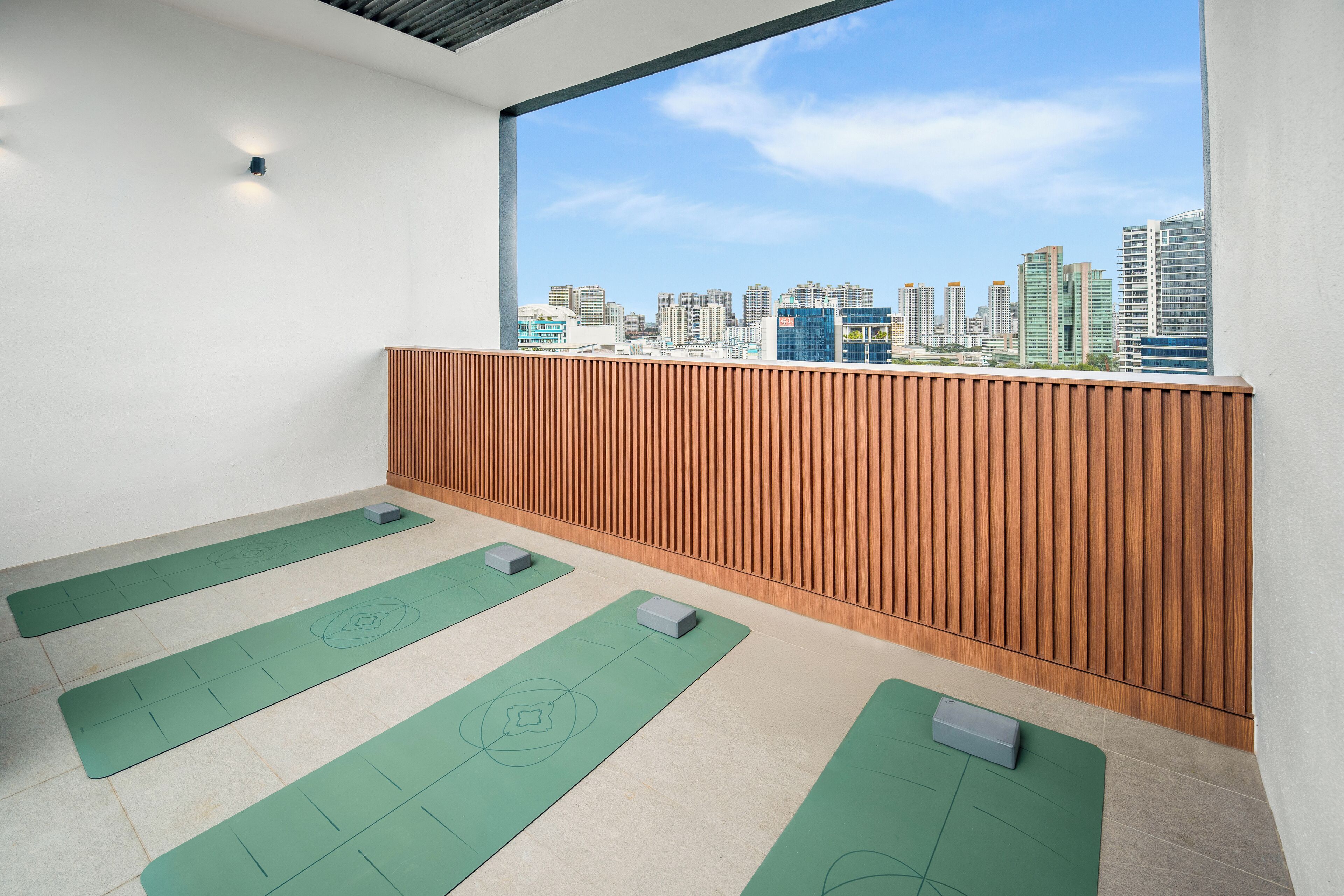 A yoga room with green mats and a city view.