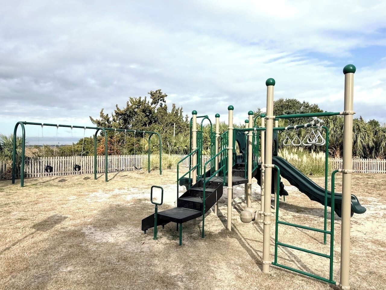 En legeplads med rutchebane, klatrestrukturer og gyngestativ.
