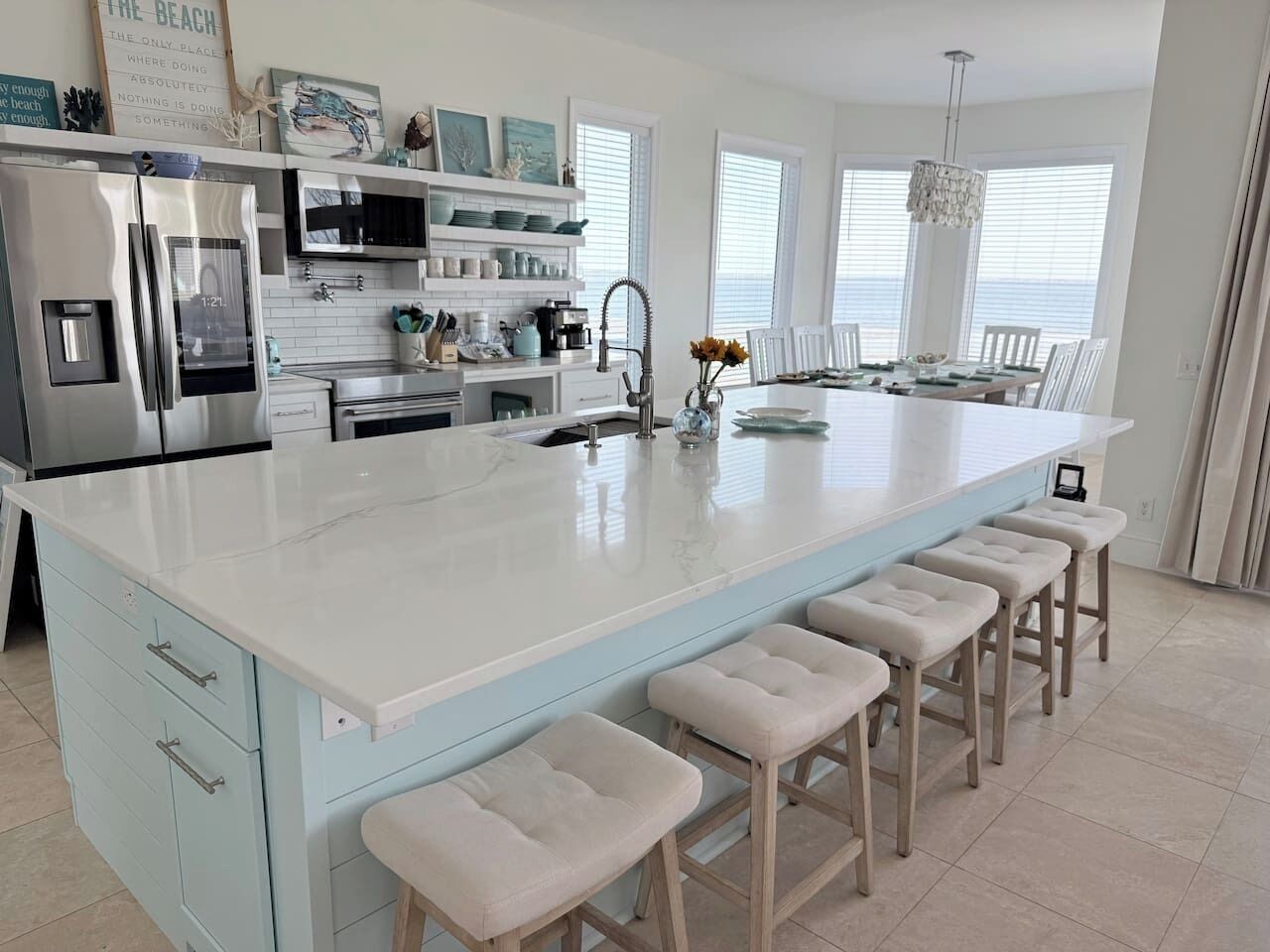 A modern kitchen with a large island, bar stools, and a dining area with a chandelier.