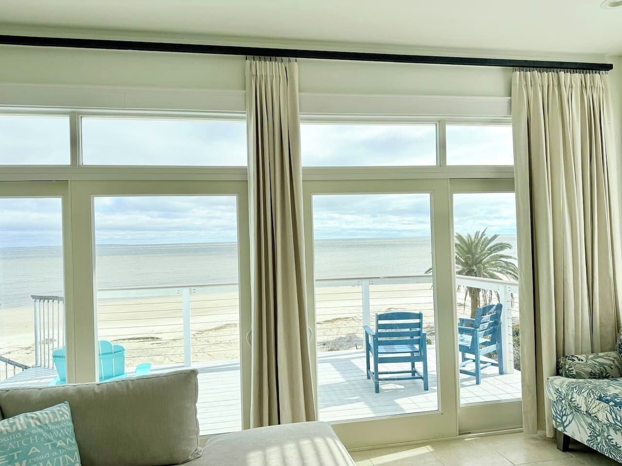Una habitación con un amplio ventanal corredizo que da a un balcón con vistas a la playa.