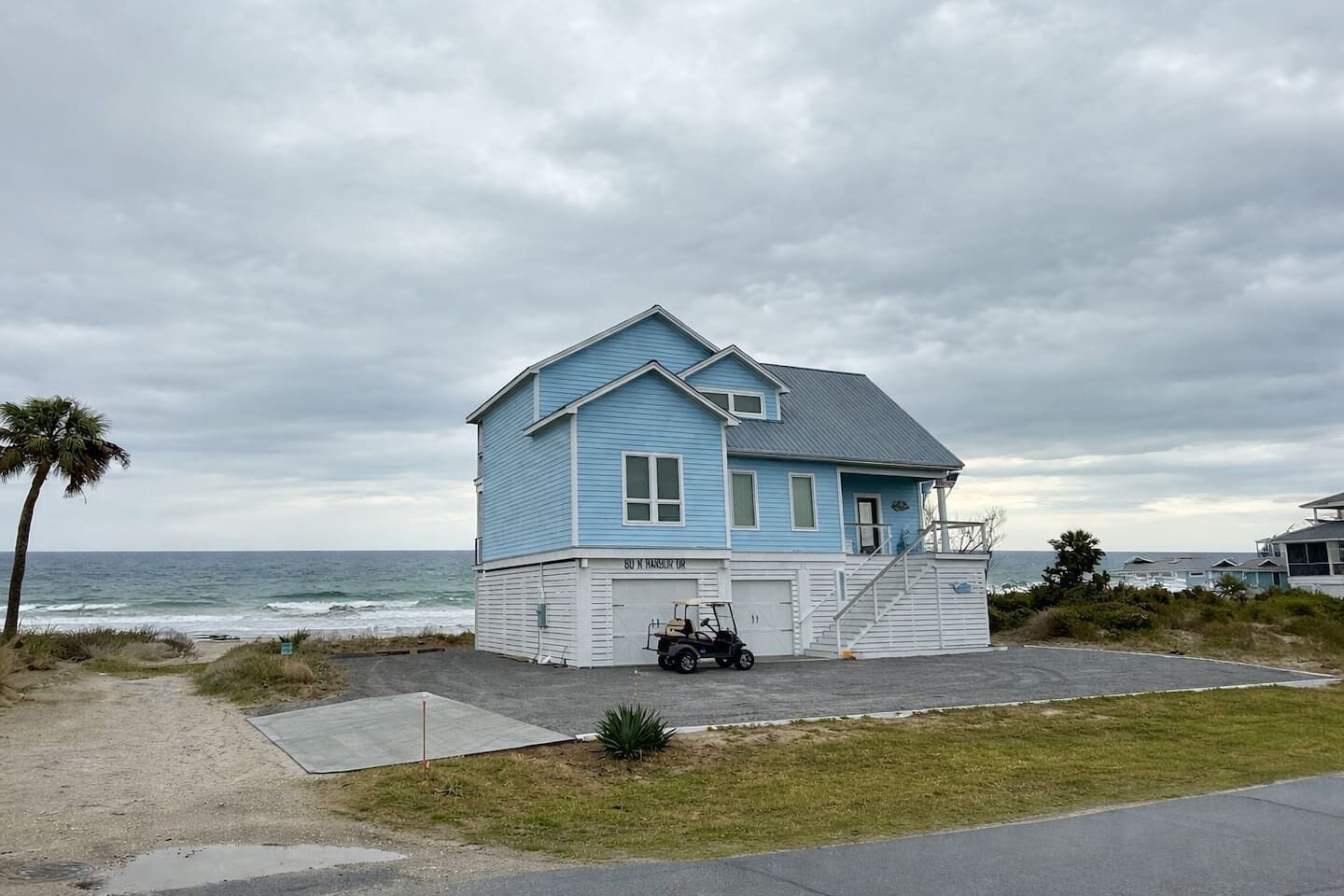 A two-story house with a garage, located near the beach with a view of the ocean.