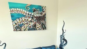 Un canapé bleu assorti d’un pouf, un tableau accroché au mur et un élément décoratif en métal.