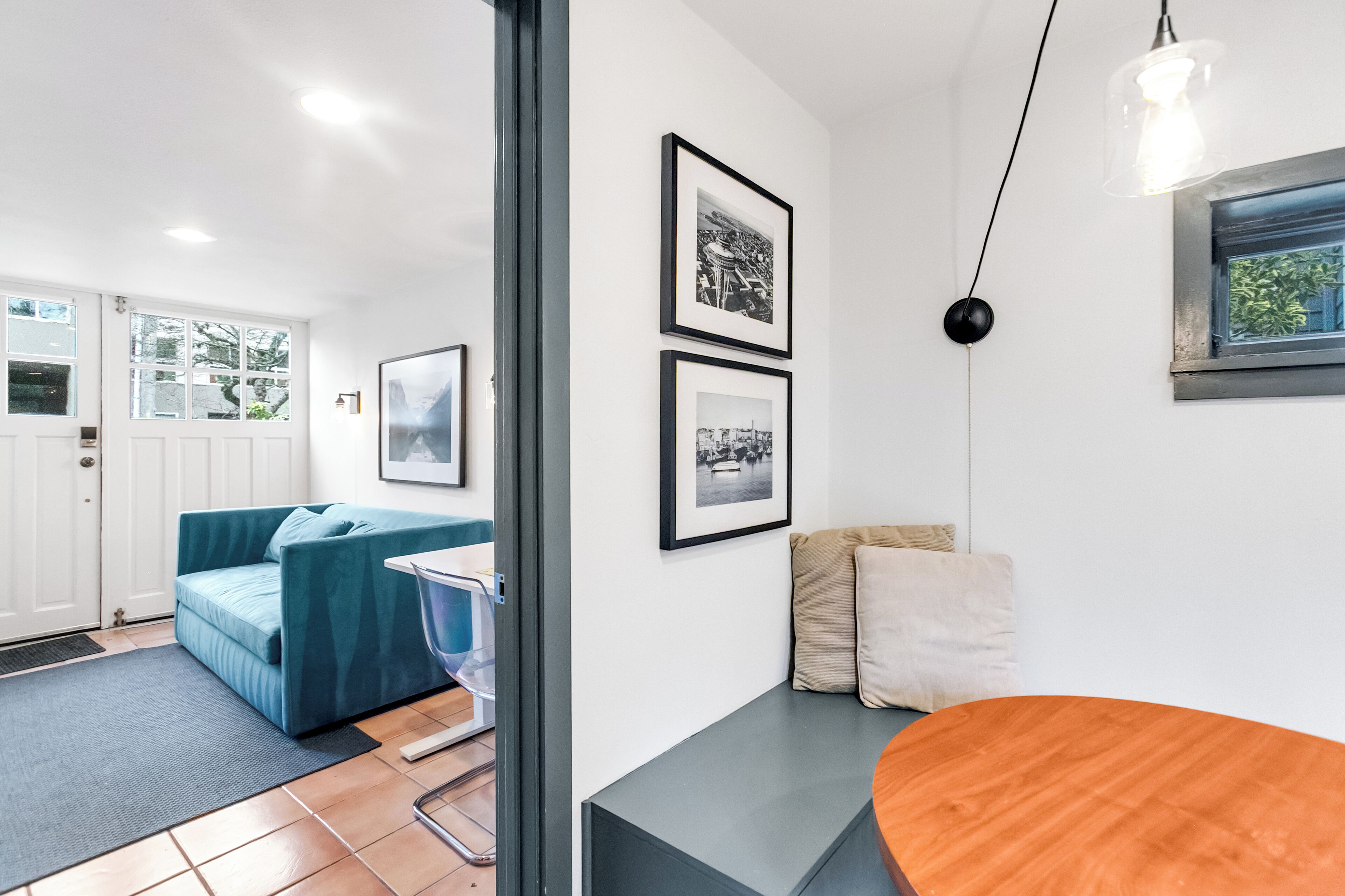 A modern living room with a teal sofa, a wooden coffee table, and framed pictures on the wall.