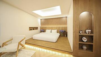Un dormitorio moderno con tragaluz, cama, cabecera de madera, una silla blanca y un mueble de madera con objetos decorativos.