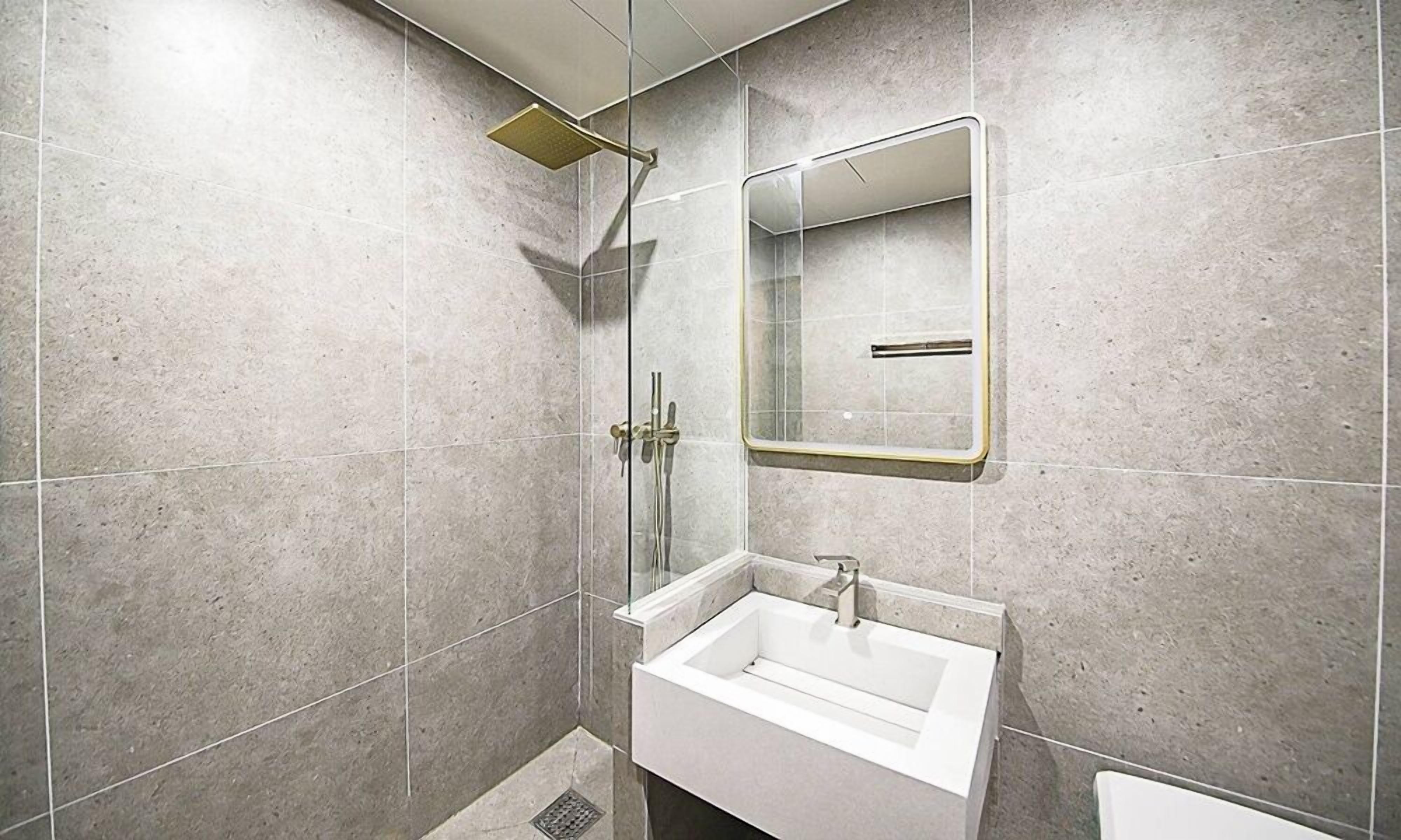 Een moderne badkamer met een douchecabine van glas, een witte wastafel en een spiegel.