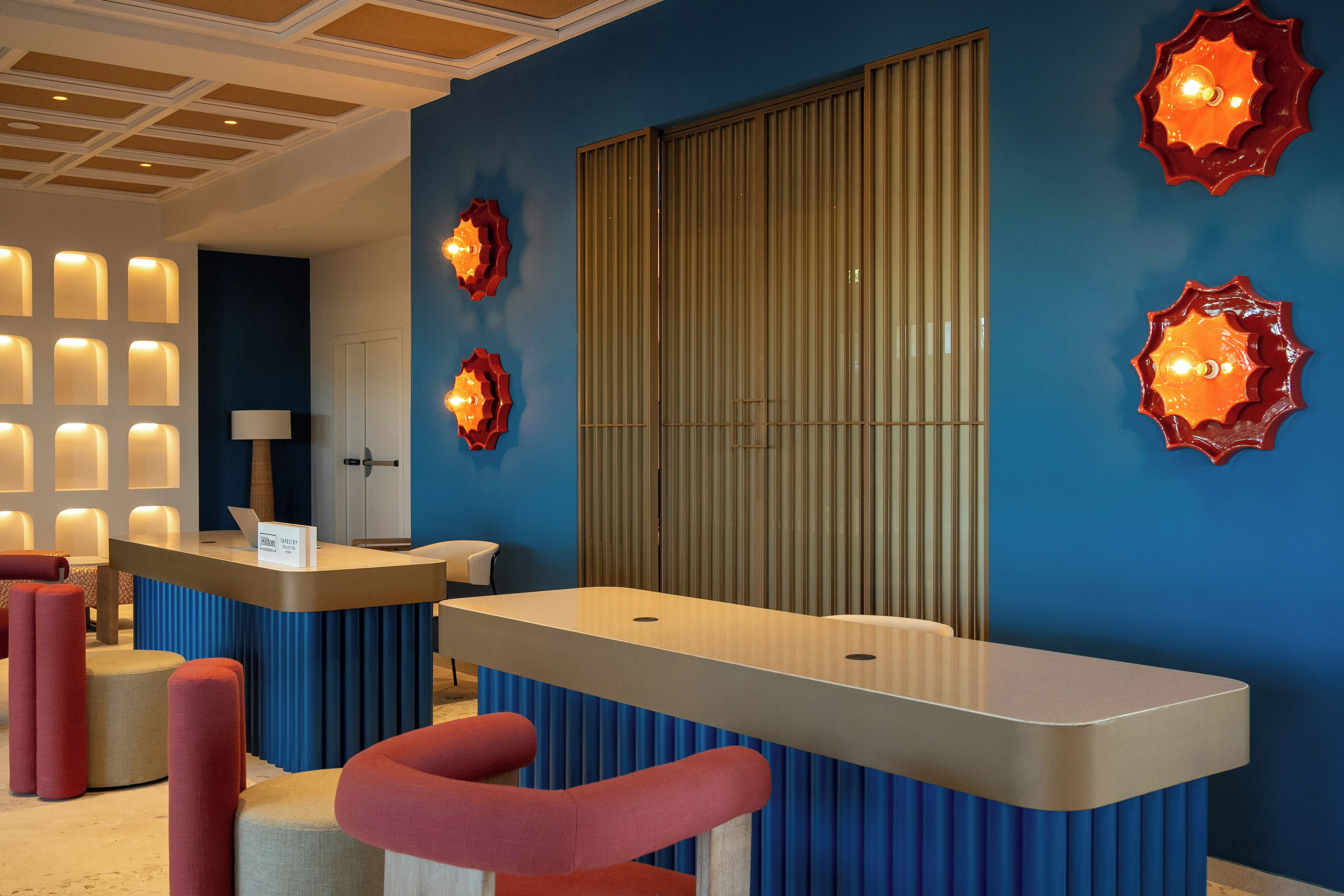A hotel reception area with a blue wall, a large window, and a reception desk.