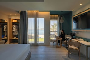 A hotel room with a bed, a desk with a laptop, a TV, and a view of the outdoors. - Terradamari Resort & Spa Marina di Modica, Tapestry Collection by Hilton (Marina di Modica)
