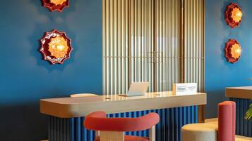 A reception desk with a laptop, a sign reading 'Hilton Tapestry Collection,' and a blue wall with vertical blinds.
