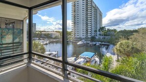 A balcony with a view of a marina, boats, and a tall building in the background. - FTL 1BR Near Beach | Pool + Free Parking (Fort Lauderdale)
