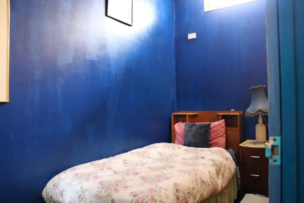 Una camera da letto con un letto singolo, un comodino, una cassettiera e una finestra.