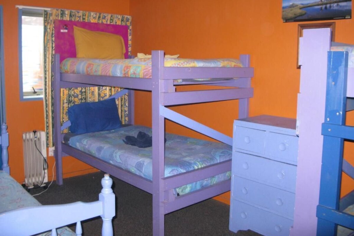 Una cama individual con literas, un aparador y una ventana con cortinas.