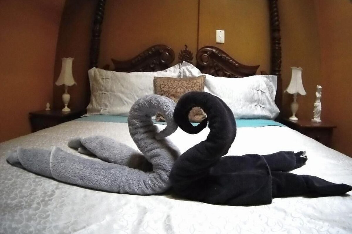 Una cama con un almohadón y una manta con forma de cisne.