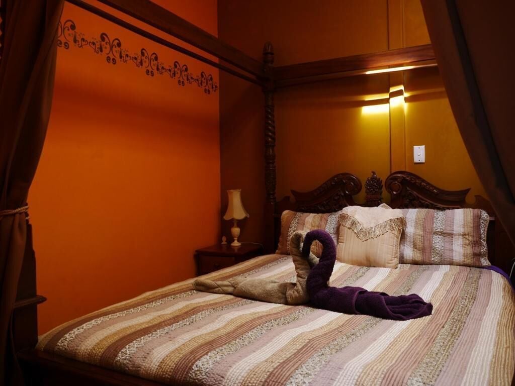 Una habitación con una cama, una mesita de noche y una pared con un diseño decorativo.