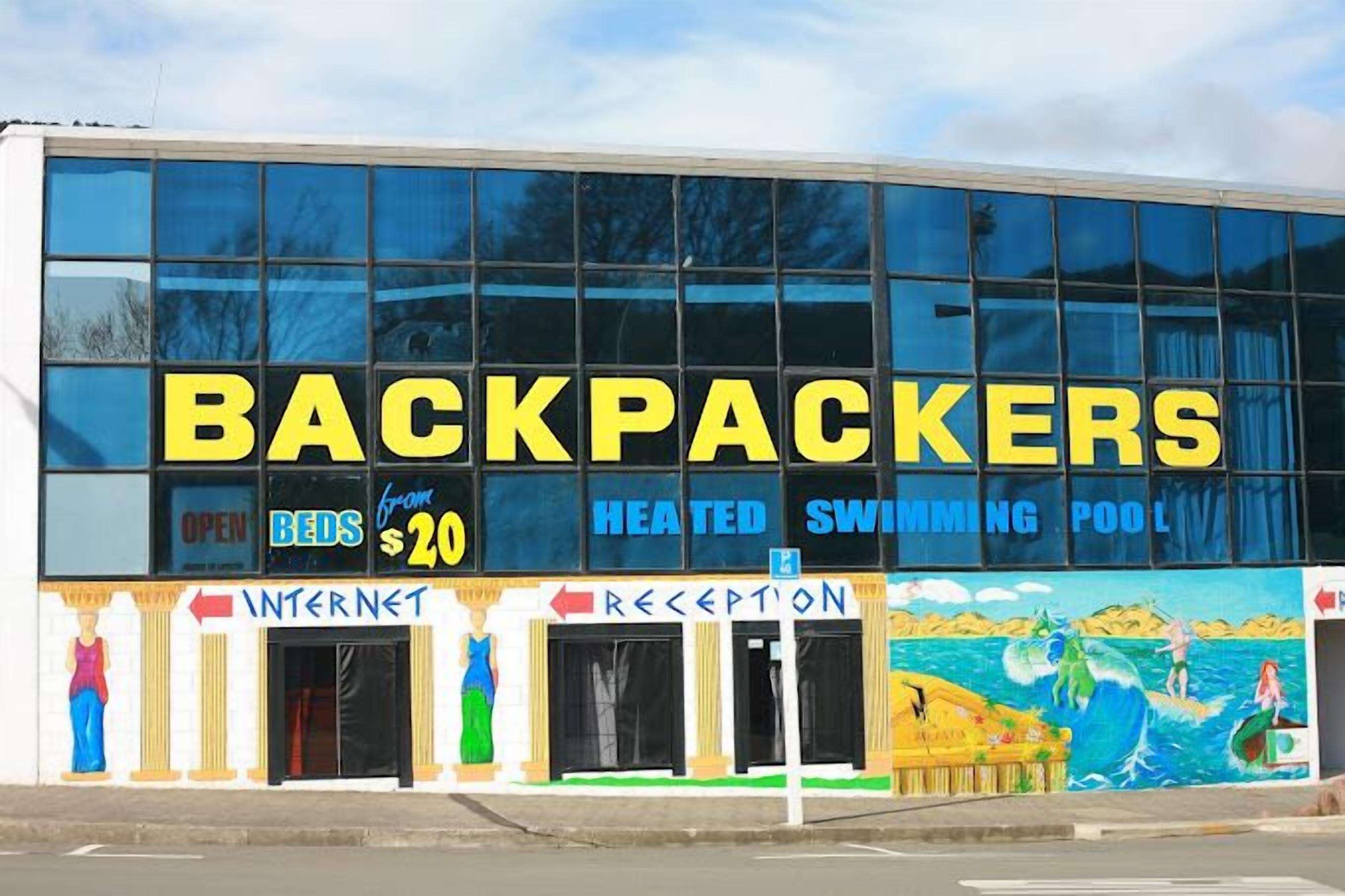 A building with a sign reading 'BACKPACKERS' and 'OPEN BEDS $20'.