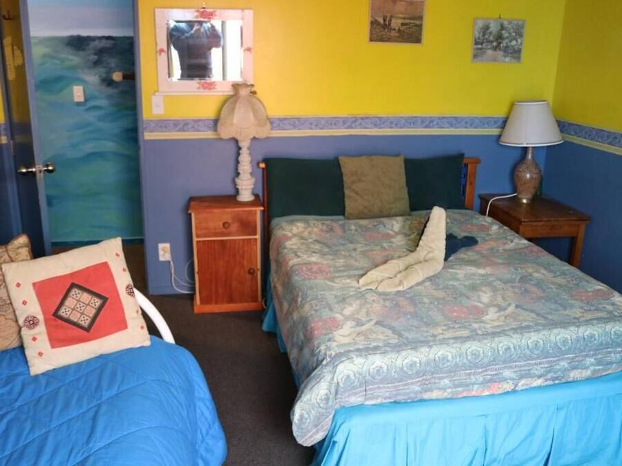 Habitació amb dos llits, una taula de nit de fusta, una làmpada i una taula petita.