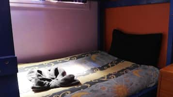 Een stapelbed met een gestreept matras, een kussen en een paar pantoffels.