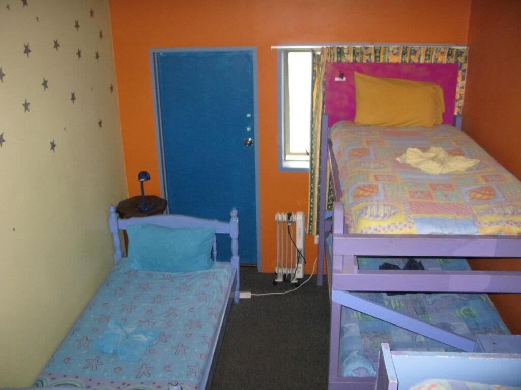 Una habitación con dos literas, una puerta, un radiador y una ventana.