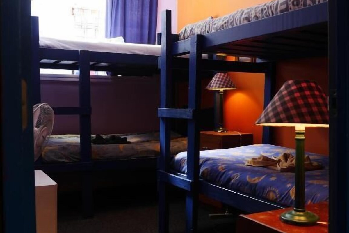 Un dormitorio con literas, un escritorio con lámpara y una ventana con cortinas.