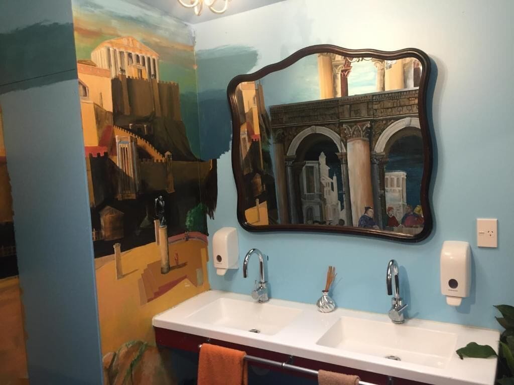 A bathroom with two sinks, a mirror, and a wall mural.