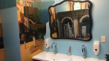 A bathroom with two sinks, a mirror, and a wall mural.