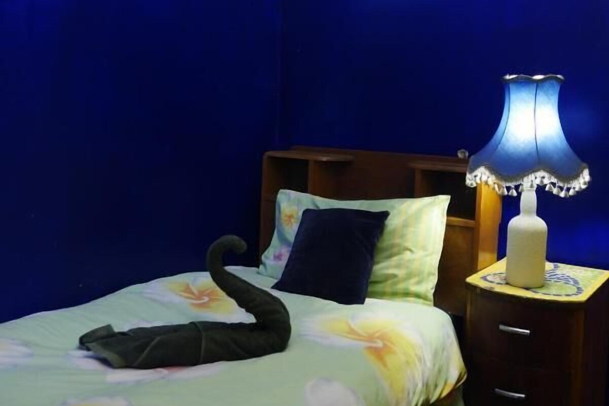 Una habitación con una cama, una mesita de noche, una lámpara y un cuadro en la pared.