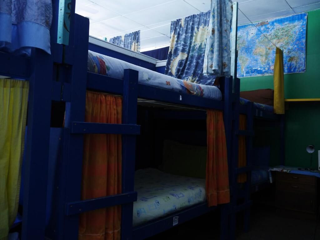 A bunk bed room with curtains, a map on the wall, and a desk.