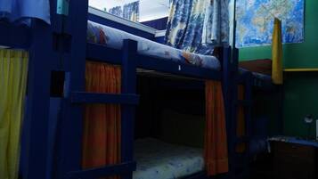 A bunk bed room with curtains, a map on the wall, and a desk.