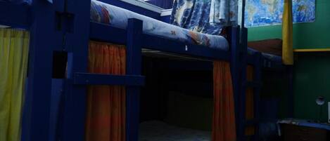 A bunk bed room with curtains, a map on the wall, and a desk.