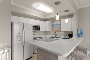 Eine moderne Küche mit weißen Schränken, einem eingebauten Backofen, einer Mikrowelle und einer großen Kochinsel mit Spüle.
