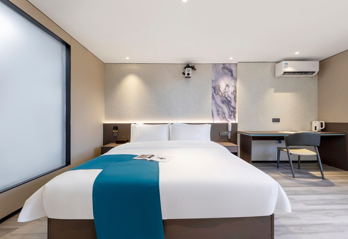 Una habitación de hotel moderna con una cama grande, un escritorio y un equipo de aire acondicionado.
