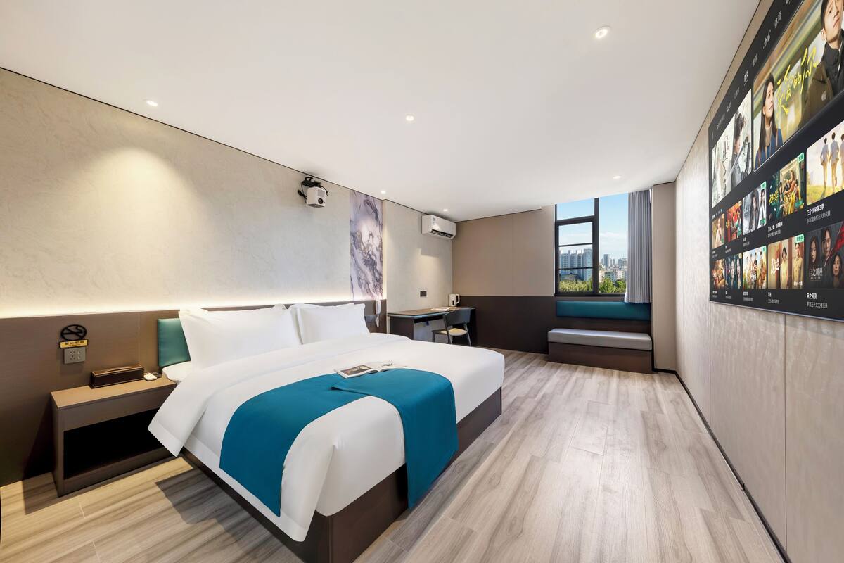 Ein modernes Hotelzimmer mit einem großen Bett, einem Schreibtisch und einer Sitzecke am Fenster.
