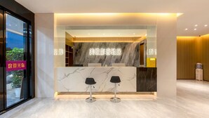 Un espace d’accueil moderne avec des comptoirs en marbre et deux tabourets de bar noirs.
