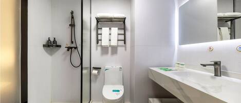 A modern bathroom with a glass-enclosed shower, a white toilet, and a marble sink with a mirror.