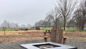 A stone patio with a black outdoor heater and a wooden chair. - Wine Country Cottage Escape (Fulton)