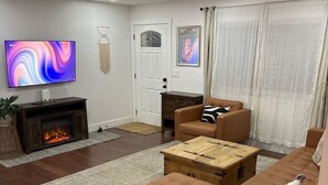 A modern living room with a fireplace, a television, a sofa, and a coffee table. - Wine Country Cottage Escape (Fulton)
