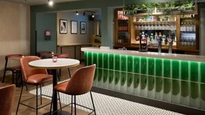 A bar area with a green bar counter, seating with cushioned chairs, and a patterned rug on the floor. - Welwyn Garden City (Welwyn Garden City)