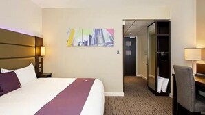 A hotel room with a large bed, a desk, and a chair. There is a painting on the wall and a closet with a mirror. - Welwyn Garden City (Welwyn Garden City)
