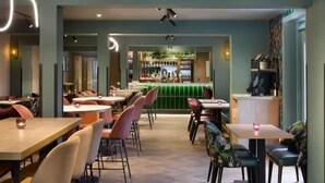 A restaurant with booths and tables, a bar area, and a counter with a green backdrop. - Welwyn Garden City (Welwyn Garden City)