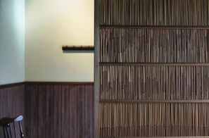 A room with a wooden panel wall, a dark wooden chair, and a white wall-mounted shelf. - Traditional Machiya | 15-minute walk to Kyoto Station (京都市下京区若宮町)
