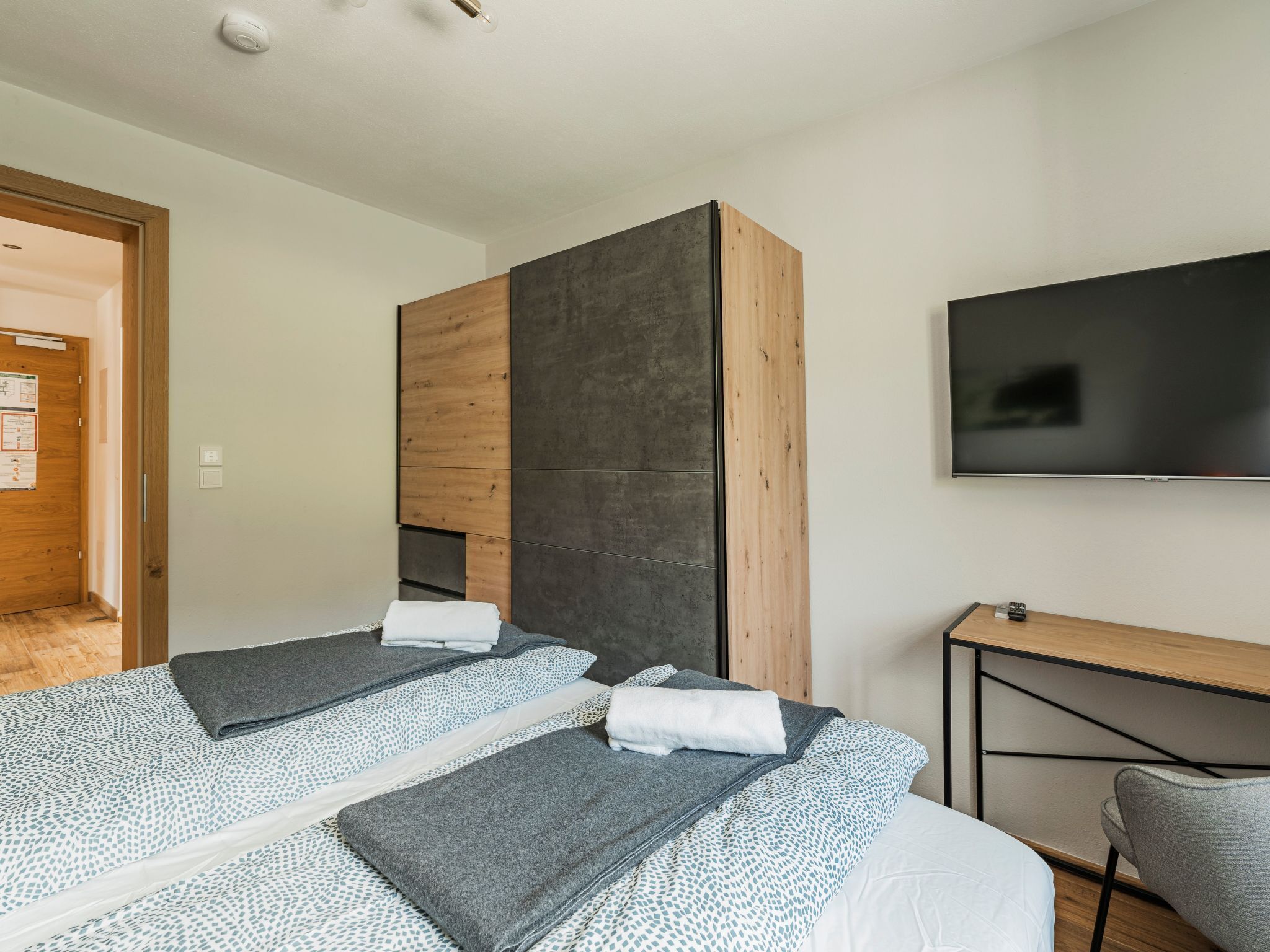 Une chambre d’hôtel moderne équipée de deux lits, d’une télévision et d’un bureau.