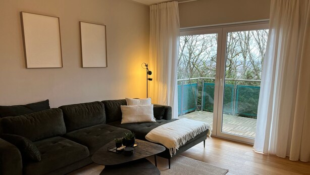 A modern living room with a dark green sofa, a small coffee table, and a balcony with a view of trees. - Top Lage Klinikum by Interhome (Saarbrücken)