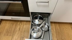 A kitchen with a built-in oven, a stainless steel range hood, and a drawer with pots and pans. - Top Lage Klinikum by Interhome (Saarbrücken)