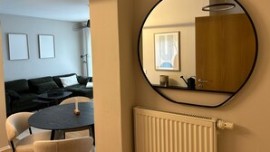 A modern room with a round mirror, a radiator, a black table with chairs, and a dark-colored sofa. - Top Lage Klinikum by Interhome (Saarbrücken)