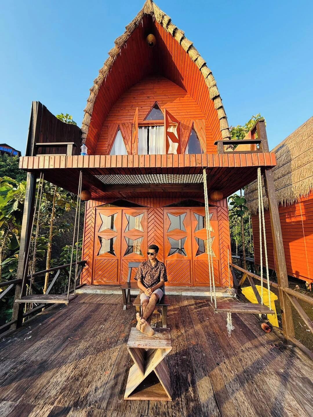 Una casa in legno con tetto di paglia, un balcone e un pontile in legno.