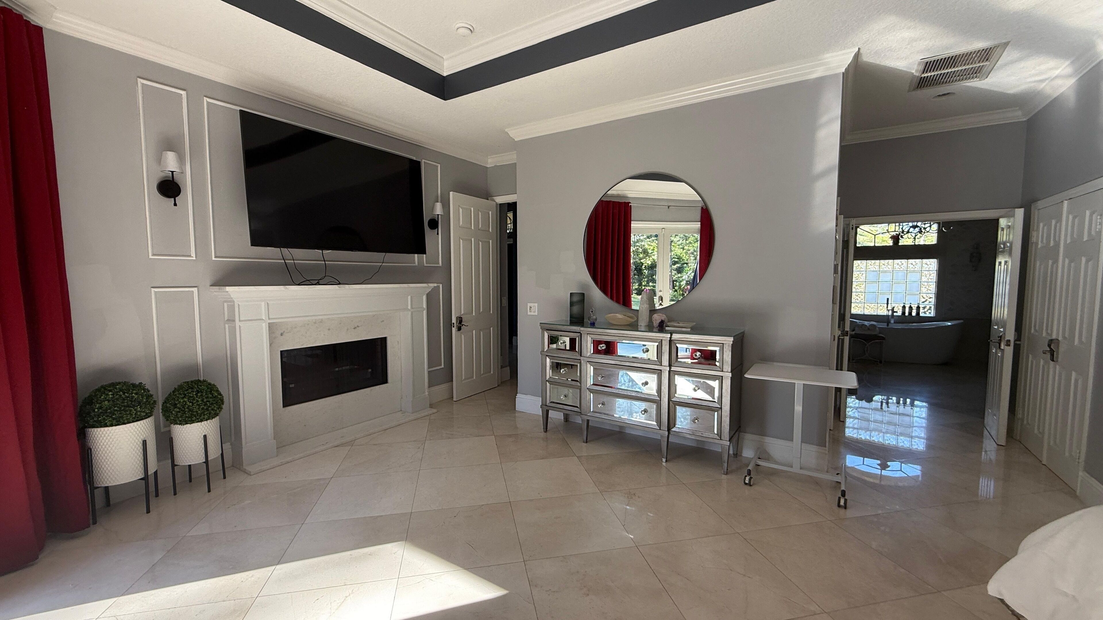 A spacious living room with a fireplace, a television, and a large mirror.