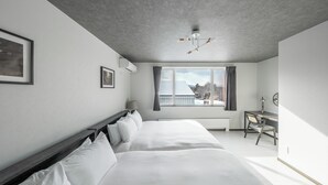 A modern hotel room with a large bed, a desk, and a view of the outside.