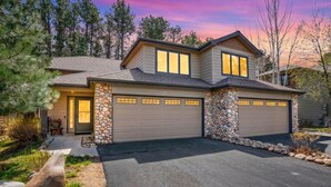 A two-story house with a stone facade, a garage, and a driveway.